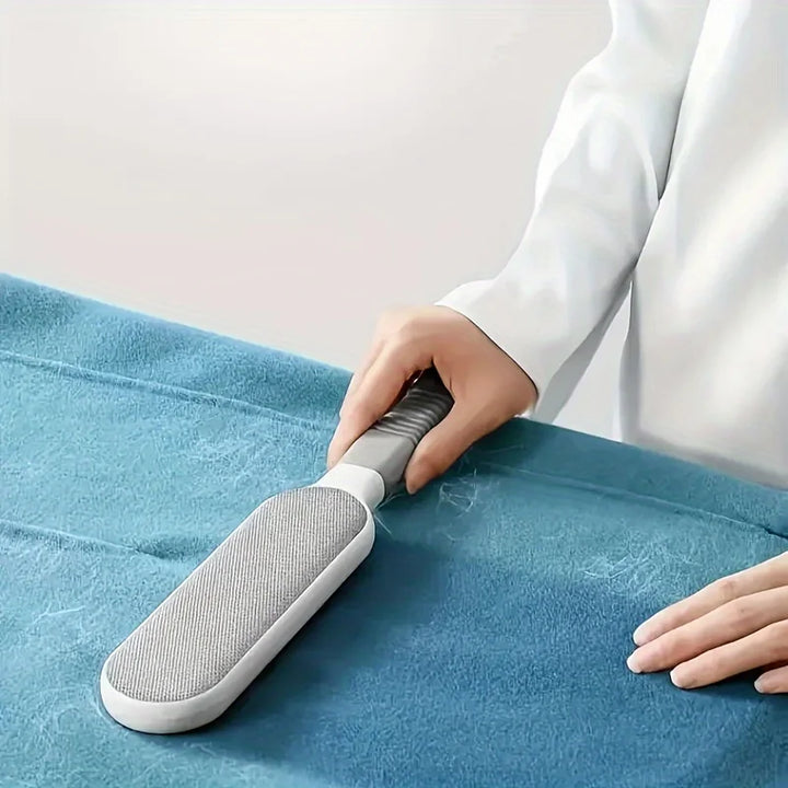 Person using a gray Pet Hair Remover brush to remove pet hair
